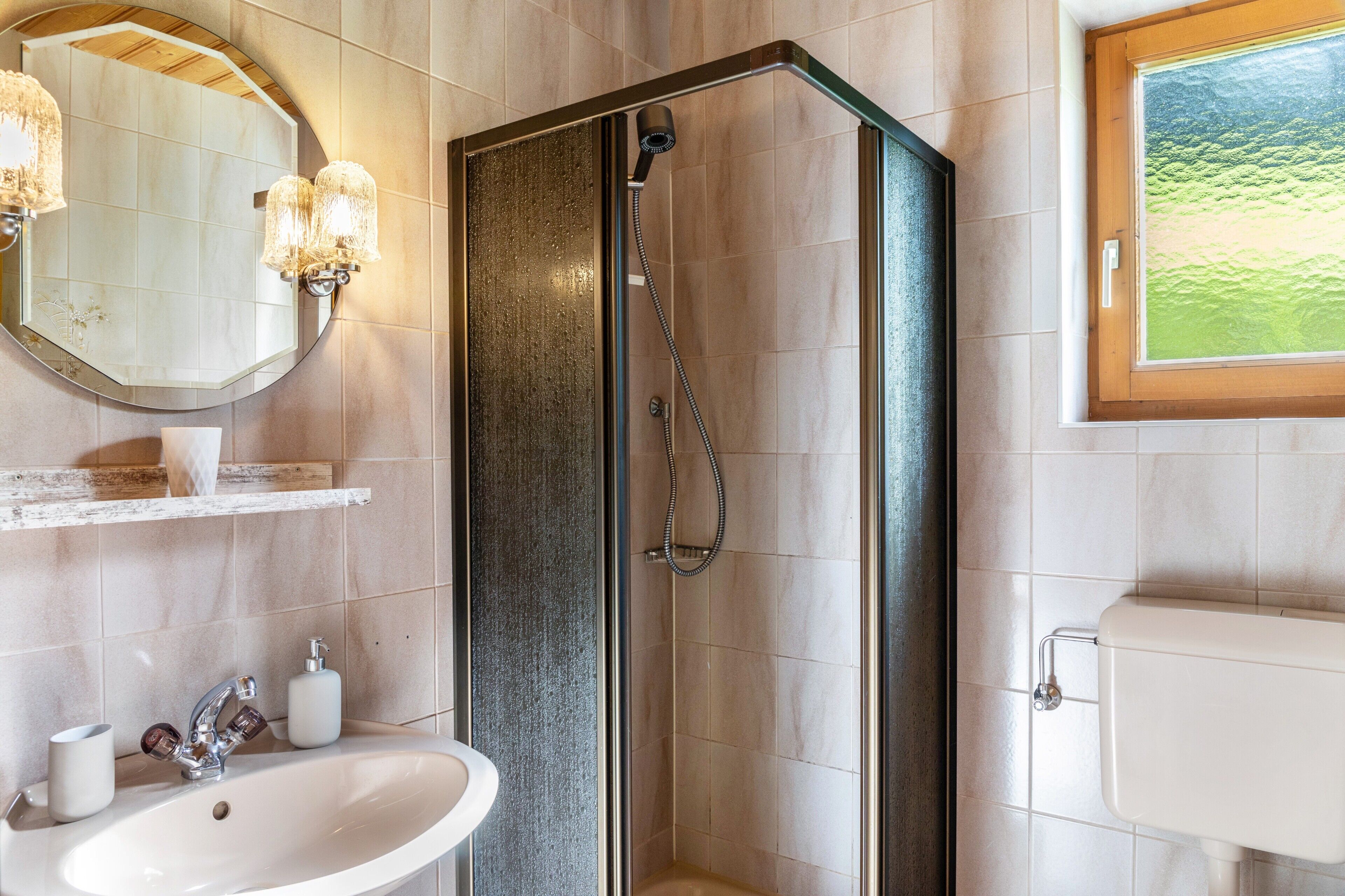 Een badkamer met douche, wastafel, spiegel en toilet.