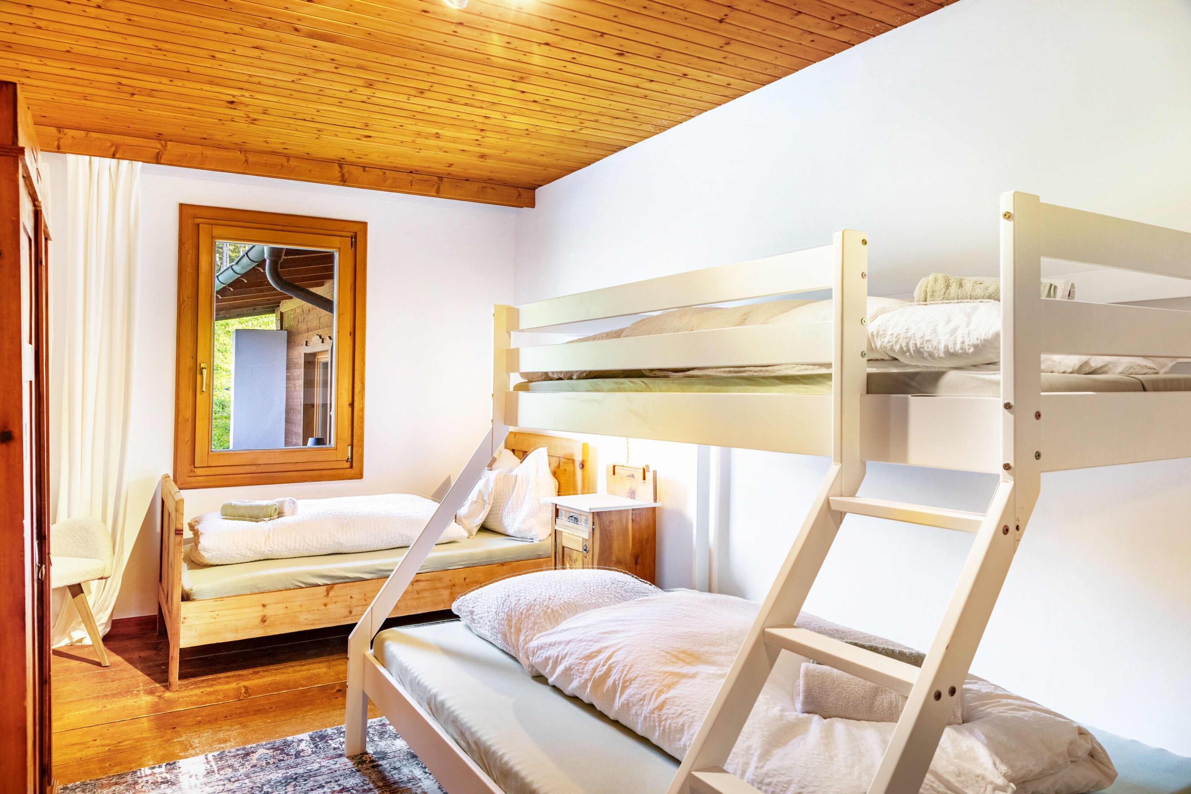 Habitación con literas, techo de madera, una ventana y un espejo.