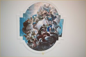 A fresco mural on a ceiling with classical figures and a central figure on a cloud.