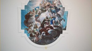 A fresco mural on a ceiling with classical figures and a central figure on a cloud.