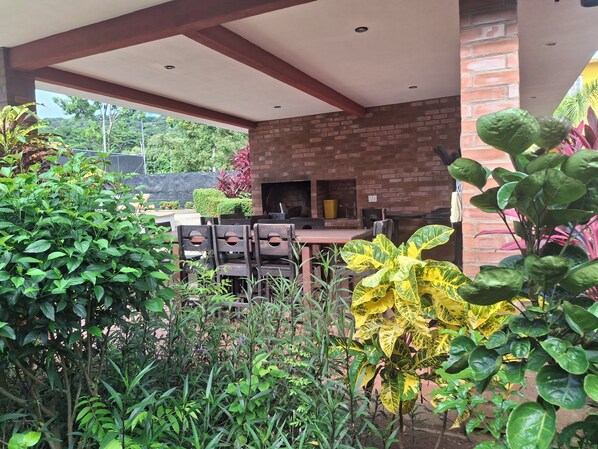Un patio exterior con paredes de ladrillo, una chimenea de ladrillo y varias sillas de madera.