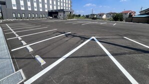 Un estacionamiento con espacios delimitados y un edificio al fondo.