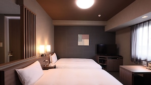 Una habitación de hotel con dos camas, un televisor de pantalla plana, un escritorio y un espejo.