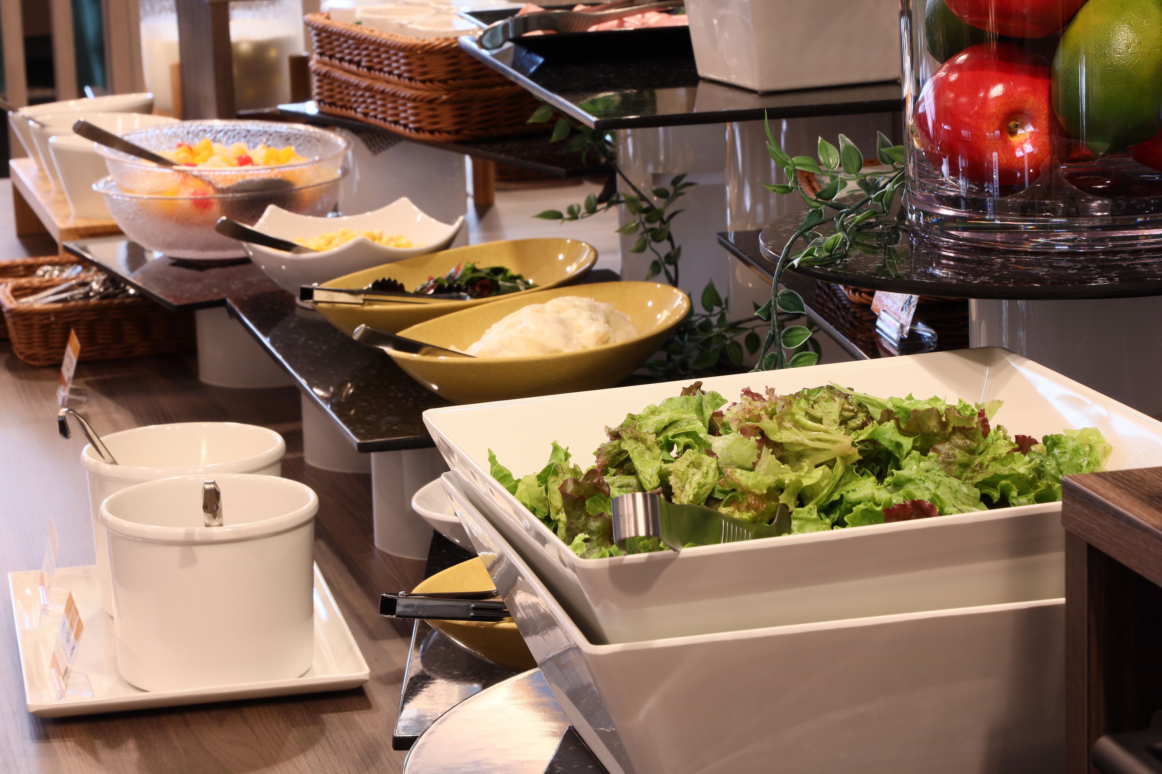 Een buffet met diverse gerechten, waaronder salades, fruit en andere maaltijden.