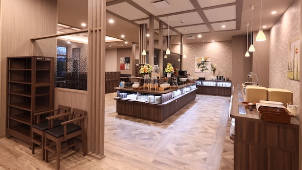 Un moderno vestíbulo de hotel con un mostrador de recepción central, sillas de madera y un suelo con estampado.
