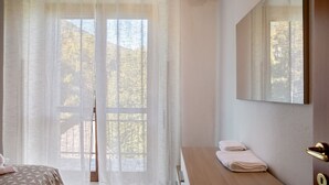 A bedroom with a bed, a wooden dresser, a mirror, and a window with sheer curtains. - Apartment 'La Terrazza' with Mountain View, Wi-Fi and Air Conditioning (Nesina)