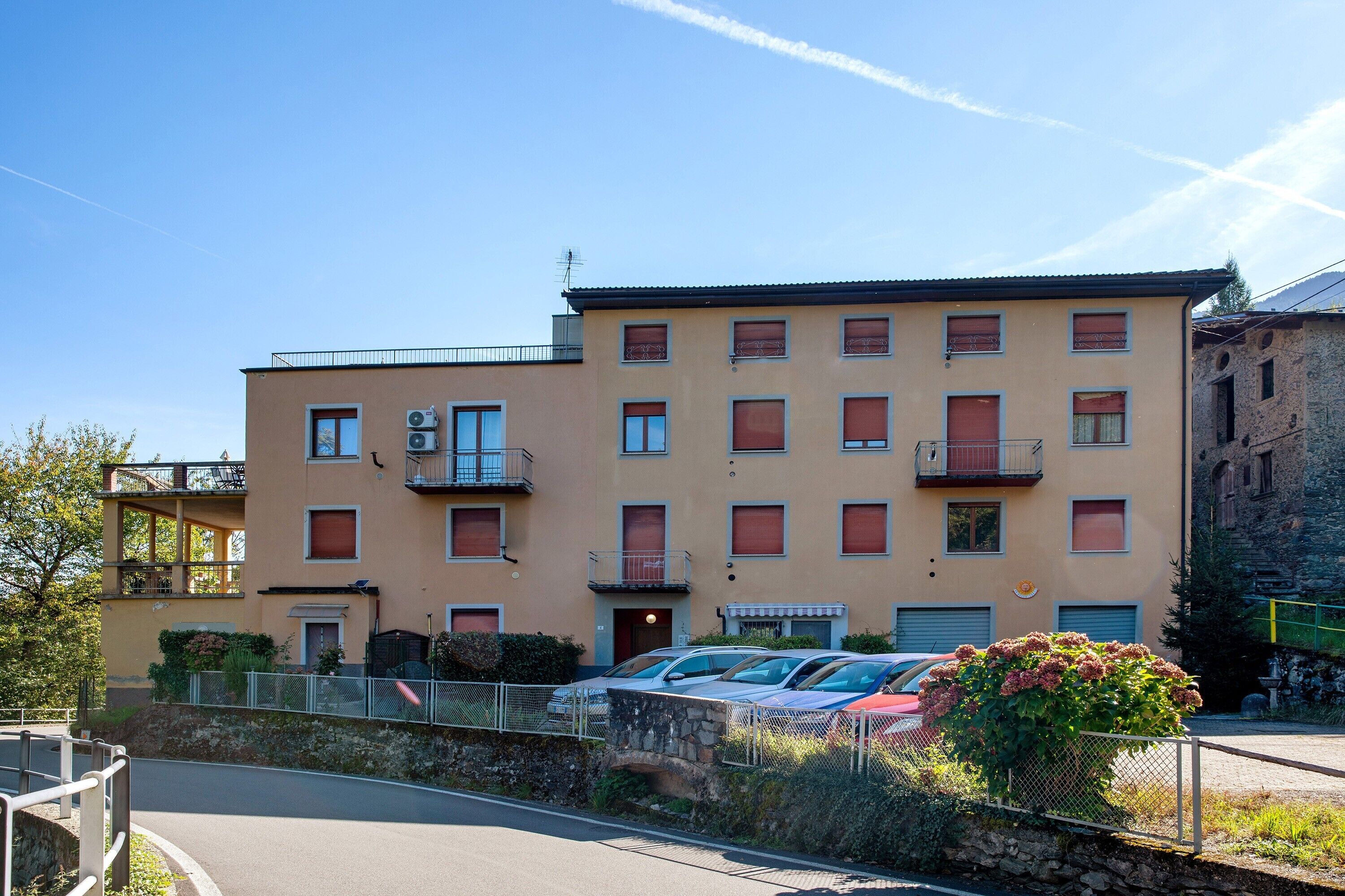 En byggnad med flera våningar, balkonger, en parkeringsplats och en mur av sten.