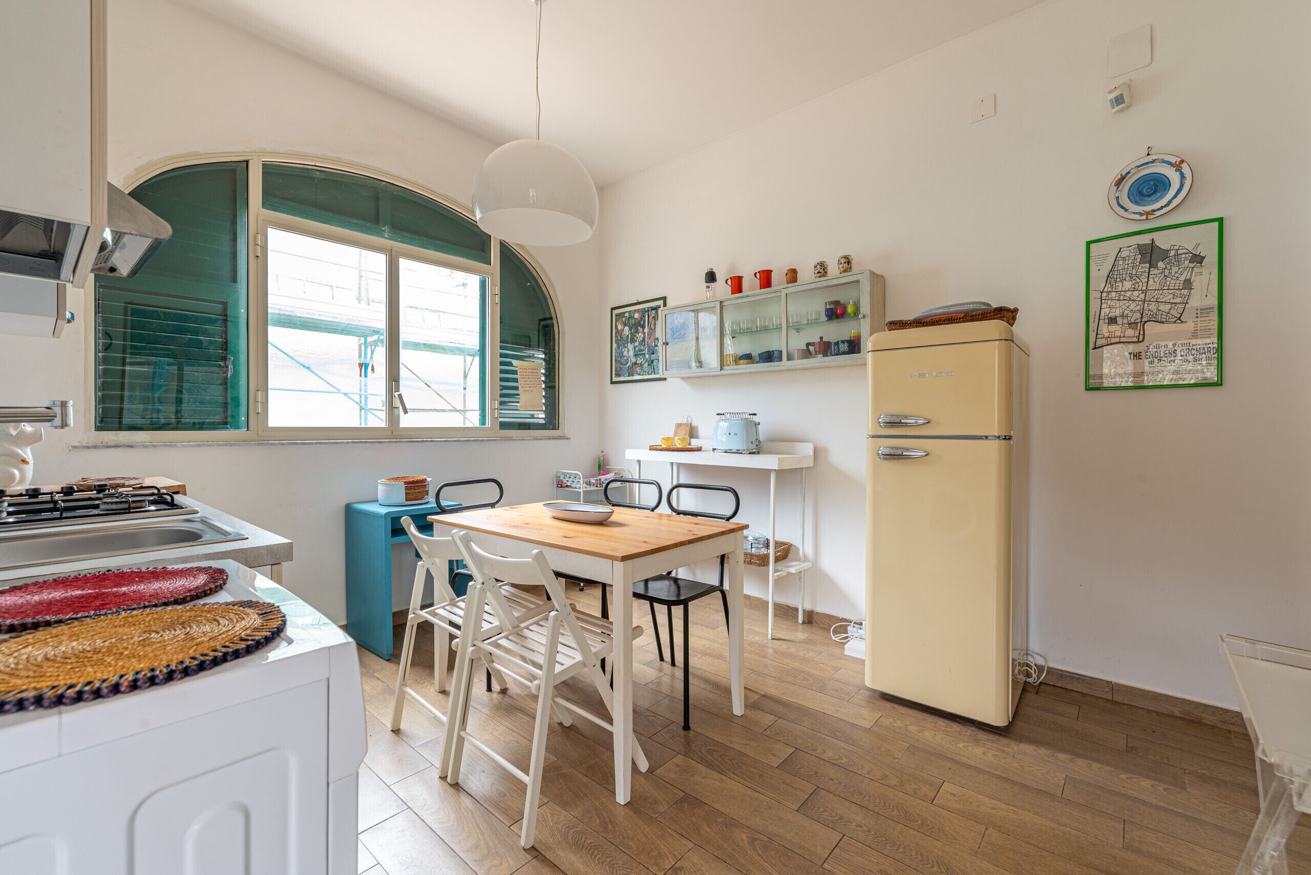 Una cucina compatta con tavolo, sedie, frigorifero e una finestra vista.