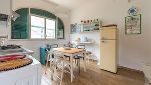 A compact kitchen with a dining table, chairs, a refrigerator, and a window with a view.