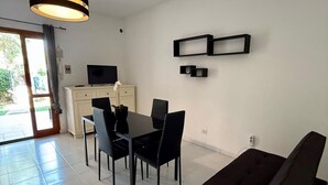 Een moderne woonkamer met een eethoek, een bank en een televisie op een kast.