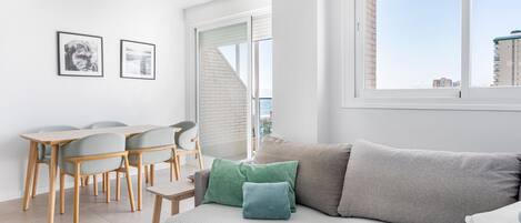 Una sala de estar moderna con un sofá, una mesa de comedor con sillas y cuadros en la pared.