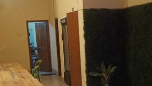 A spacious room with a wooden table, a potted plant, and a wall with a green textured design. - Hotel Cosy Home (Guwahati)