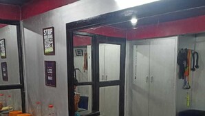 A gym with exercise equipment, a mirror, and motivational posters on the walls. - Hotel Cosy Home (Guwahati)