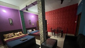 A room with a bed, a sofa, a coffee table, and a dining table with chairs. - Hotel Cosy Home (Guwahati)
