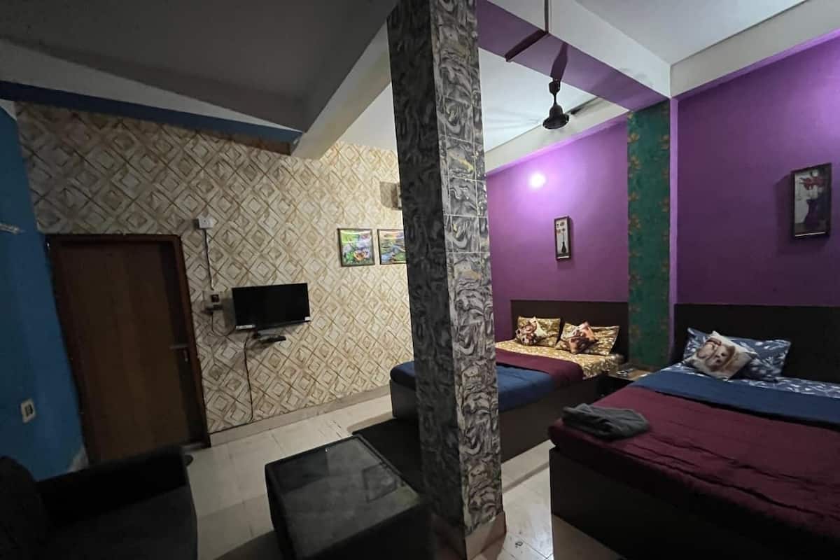 Una habitación con cama, sofá, televisor y un pilar.