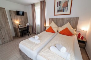 A hotel room with two beds, a desk, a TV, and a painting on the wall. - Hotel Lichtblick (Salach)