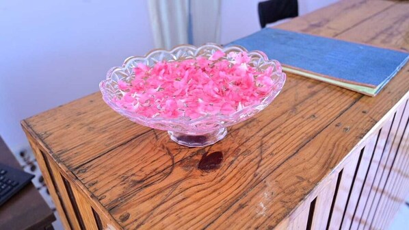 Un saladier en verre rempli de fleurs roses, posé sur une table en bois.