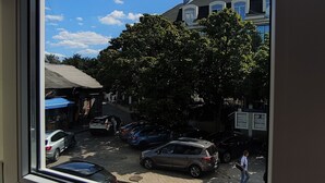 A view from a window of a street with parked cars, a tree, and buildings.