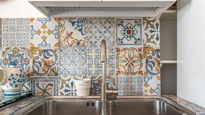 A kitchen with a double sink and colorful tile backsplash.