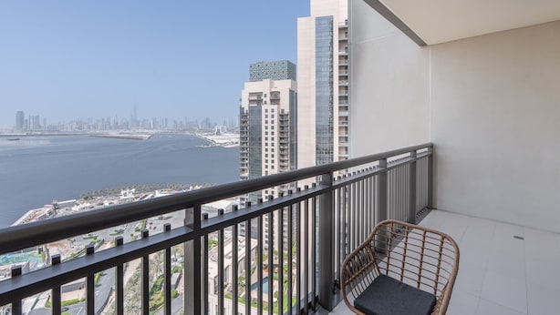 Un balcon donnant sur les toits d’une ville et sur une étendue d’eau.