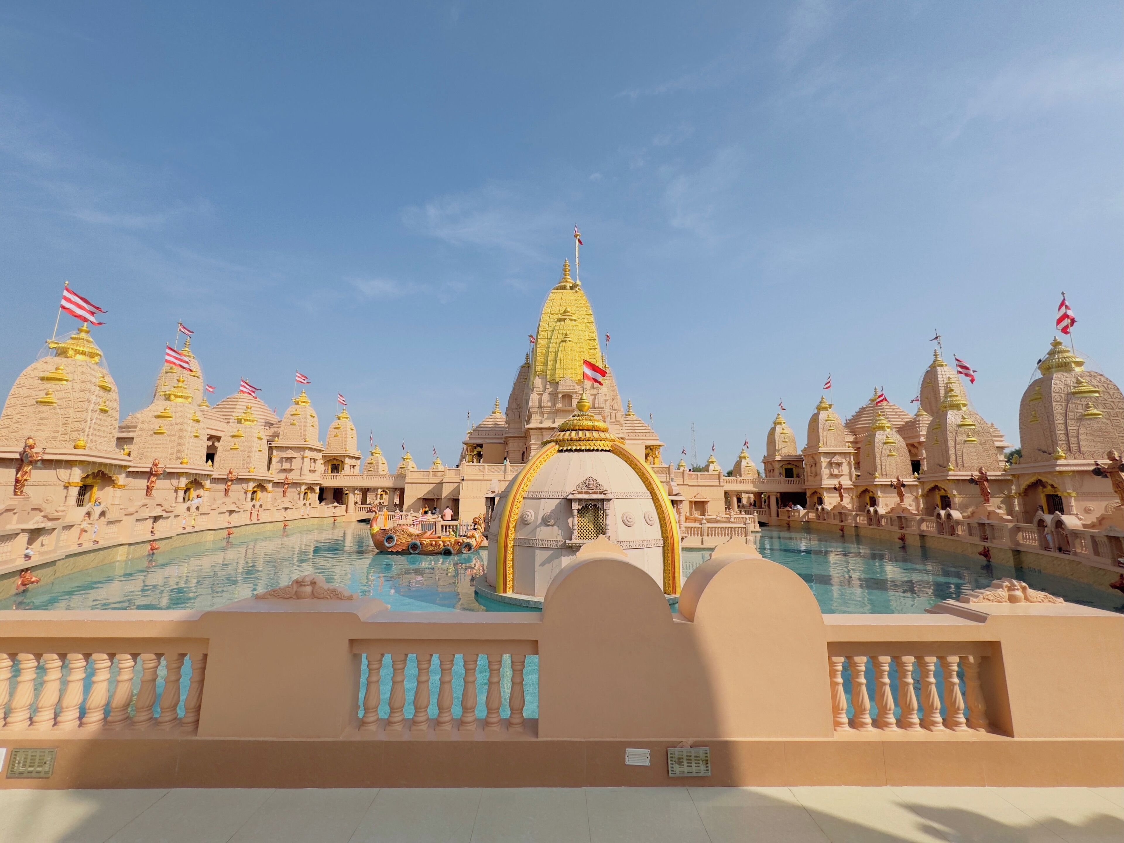 A temple complex with multiple domed structures, a central golden spire, and a pool area.