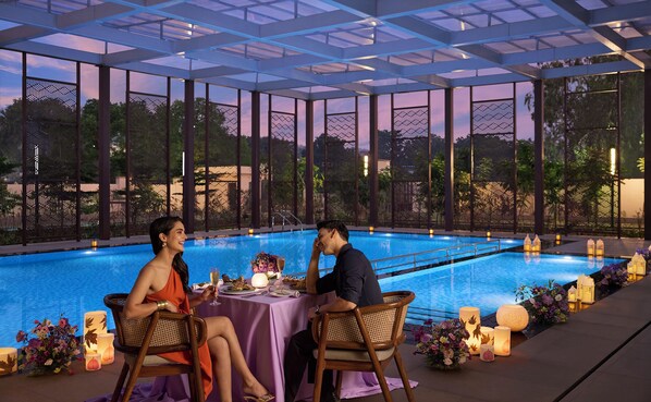 A couple dining by a pool with a view of the sky and trees. - Vivanta Ekta Nagar, Statue of Unity (Garudeshwar)