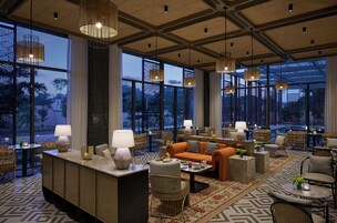 A spacious hotel lobby with large windows, a central seating area, and a variety of seating options.