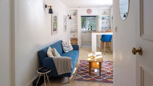 Una sala de estar moderna con un sofá azul, una mesita auxiliar pequeña y una alfombra colorida.