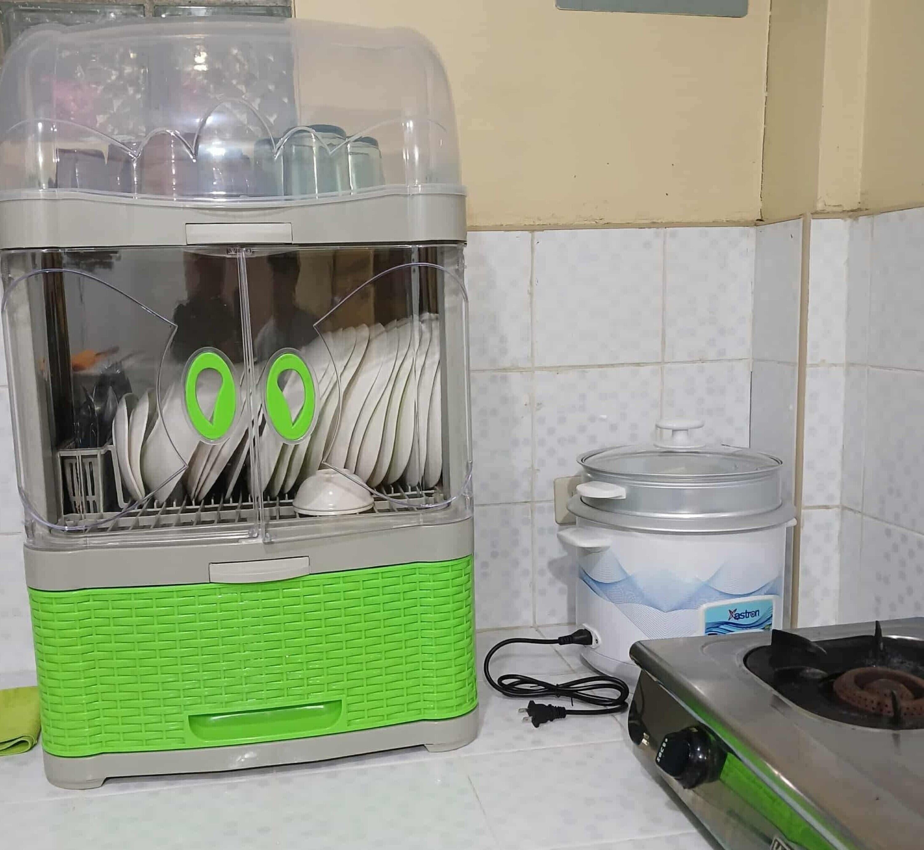 A kitchen with a dishwashing machine, a large water container, and a stove.