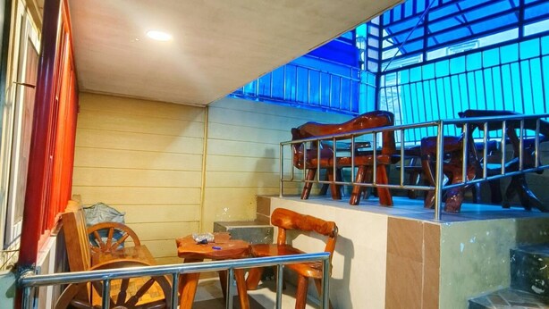 A room with a wooden chair, a table, and a metal railing. - Comfortable Stay in Baguio City (Baguio)