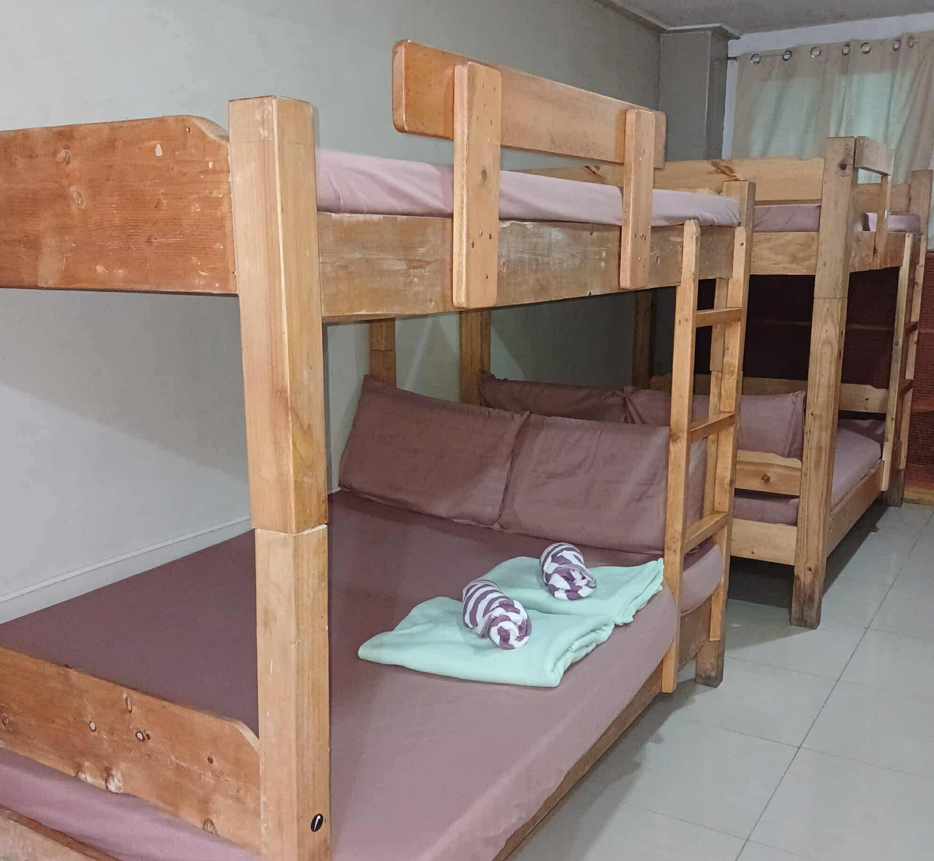 Quarto com beliches de madeira e roupa de cama roxa.