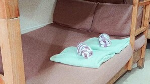 A bunk bed with a single lower bunk and a top bunk. The lower bunk has a pink mattress and a green blanket. There are two rolled-up towels on the mattress. - Comfortable Stay in Baguio City (Baguio)