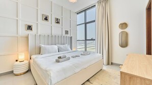 Une chambre moderne avec un grand lit, une table de chevet avec une lampe et une vue sur la ville grâce à une grande fenêtre.