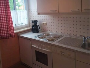 A kitchen with a window, a coffee maker, a stove, and a dishwasher.