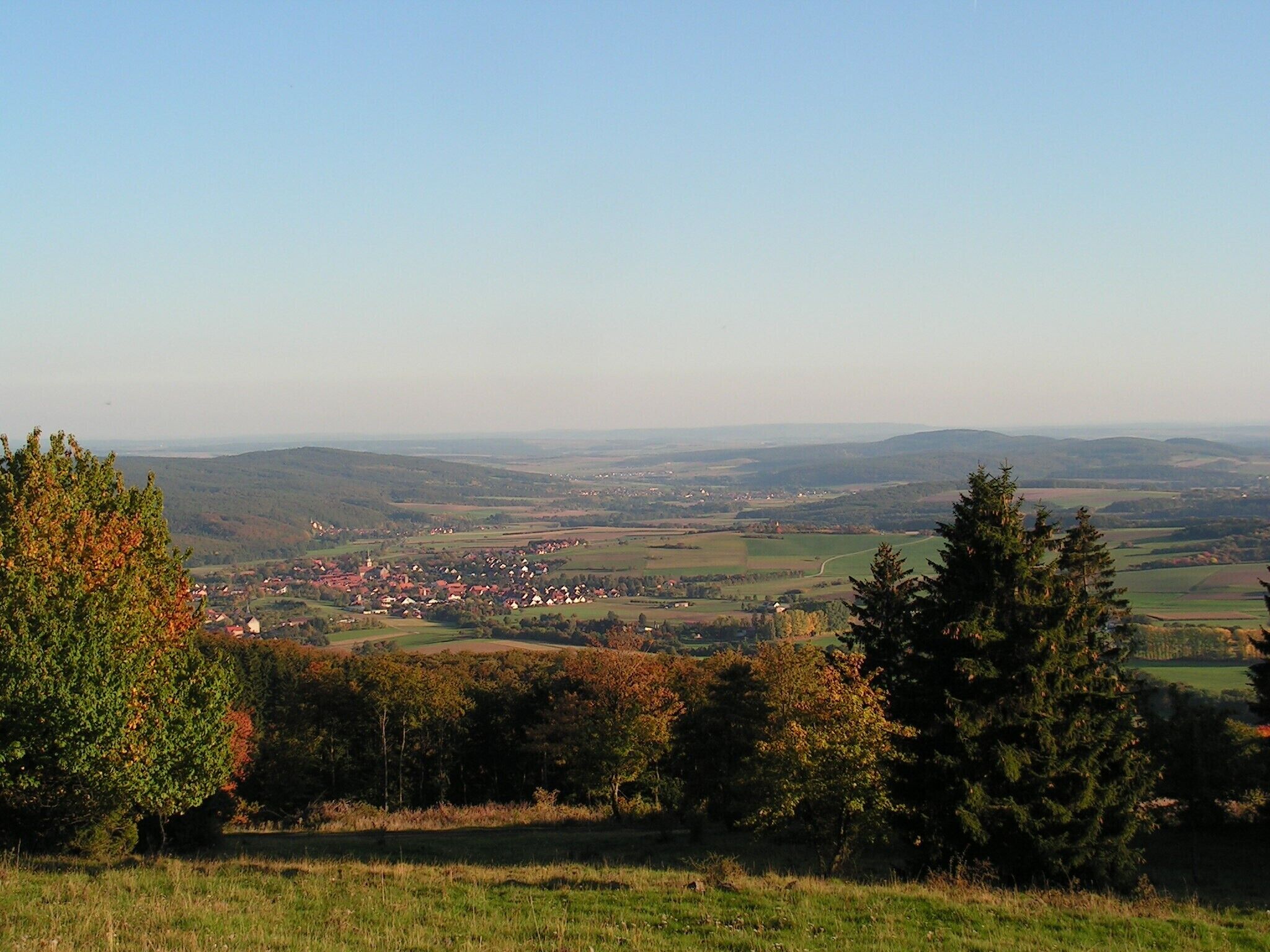 Una vista panorámica de un pueblo enclavado en un valle, con colinas onduladas al fondo.