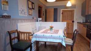 Un coin repas avec une table dressée pour deux personnes, un banc en bois et une chaise.