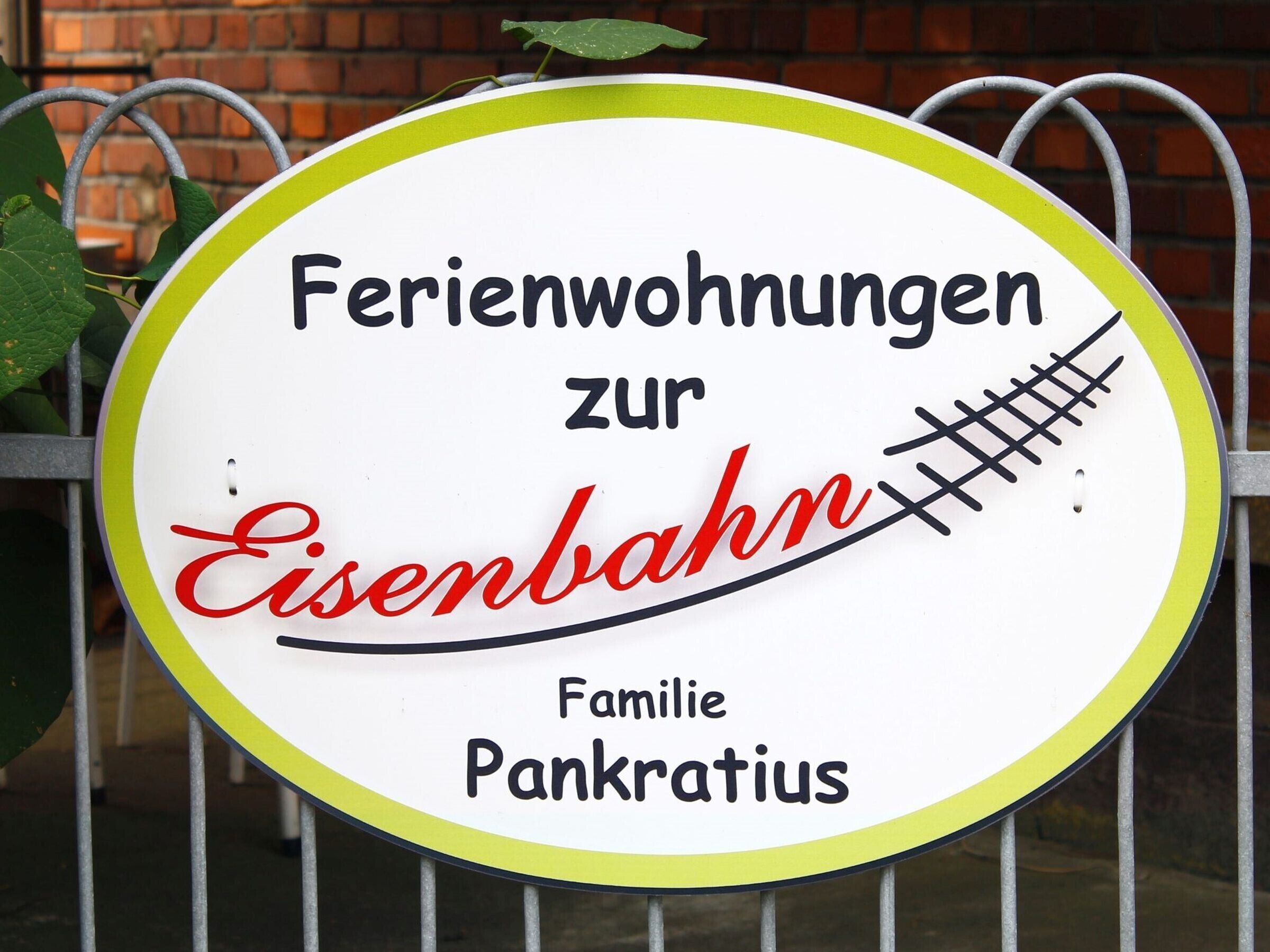 Schild mit dem Text 'Ferienwohnungen zur Eisenbahn Familie Pankratius', das ein familiengeführtes Gästehaus kennzeichnet.