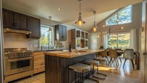 A modern kitchen with a central island, bar stools, and a dining area with chairs.