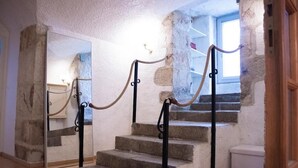 A staircase with a rope barrier, a mirror reflecting the stairs, and a window with daylight. - Charme rare sous les voûtes accommodation in Royat (Royat)