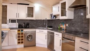 A compact kitchen with white cabinets, a washing machine, and a dishwasher. - Charme rare sous les voûtes accommodation in Royat (Royat)