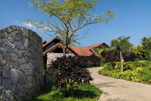 A stone wall, a pathway, and a building with a red roof. - Greenpark Resort  and Spa Madikeri (Madikeri)
