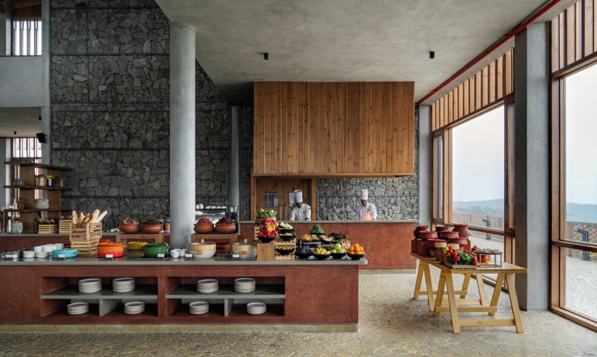 A modern kitchen with a stone wall, wooden cabinets, and a buffet counter with various dishes and utensils.