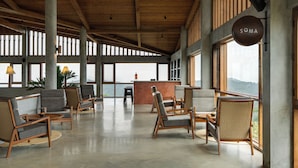 A spacious lobby with wooden furniture, large windows, and a reception desk.
