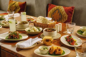 A table set with various dishes, including rice, curry, and bread, along with glasses of water and tea. - Greenpark Resort  and Spa Madikeri (Madikeri)