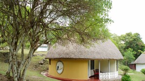 A thatched-roof structure with a circular window and a small porch. - Bayside Resort Lake Victoria (Mbita)