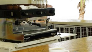 A coffee machine, shelves with beverages, and a palm tree in the background. - Bayside Resort Lake Victoria (Mbita)