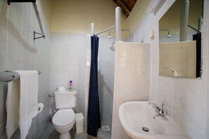 Casa de banho com sanita, lavatório e chuveiro.