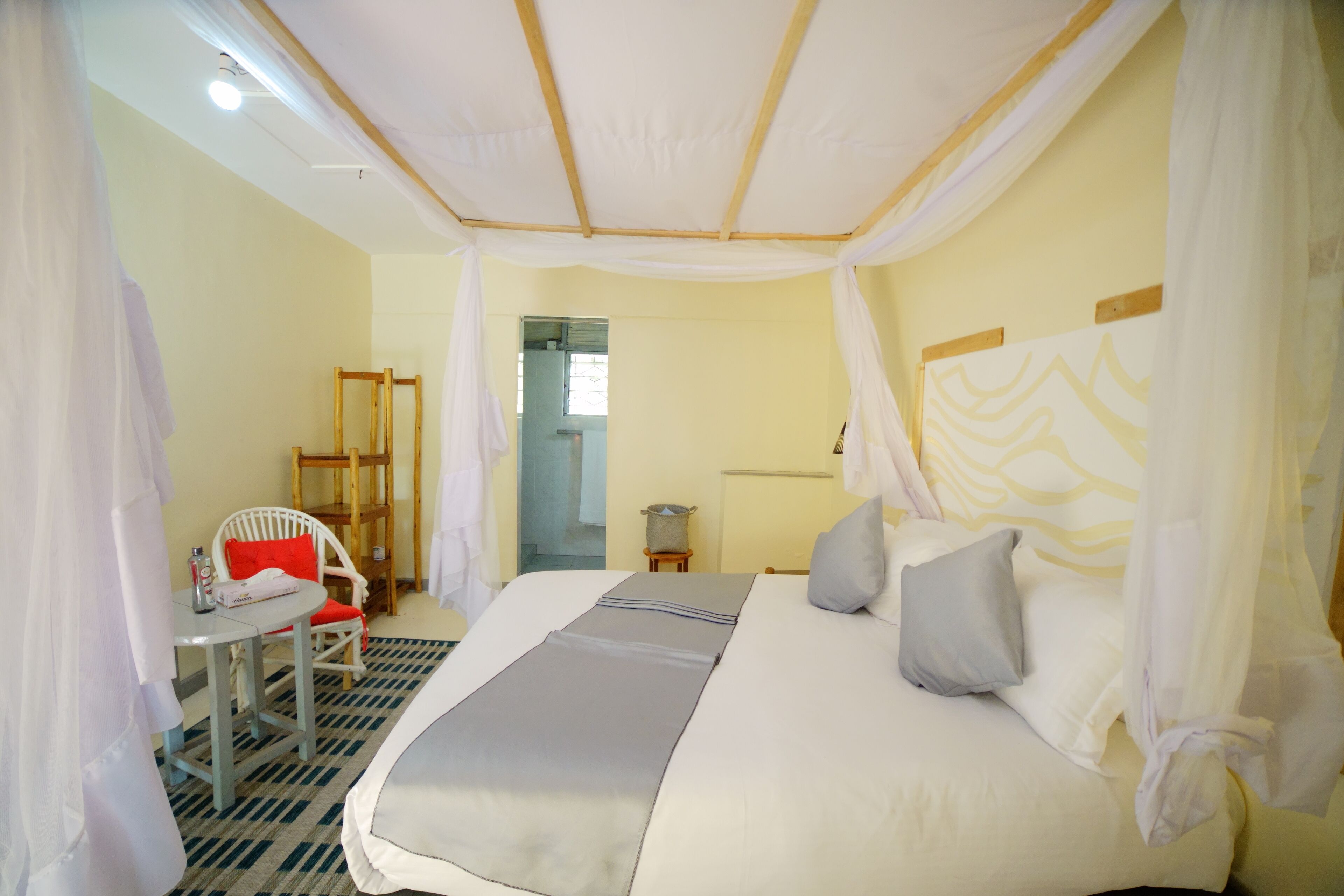A bedroom with a bed, a chair, a table, and a mirror.