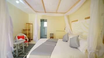 A bedroom with a bed, a chair, a table, and a mirror.