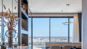 A modern interior with a dining area, a sofa, and a view of the city.